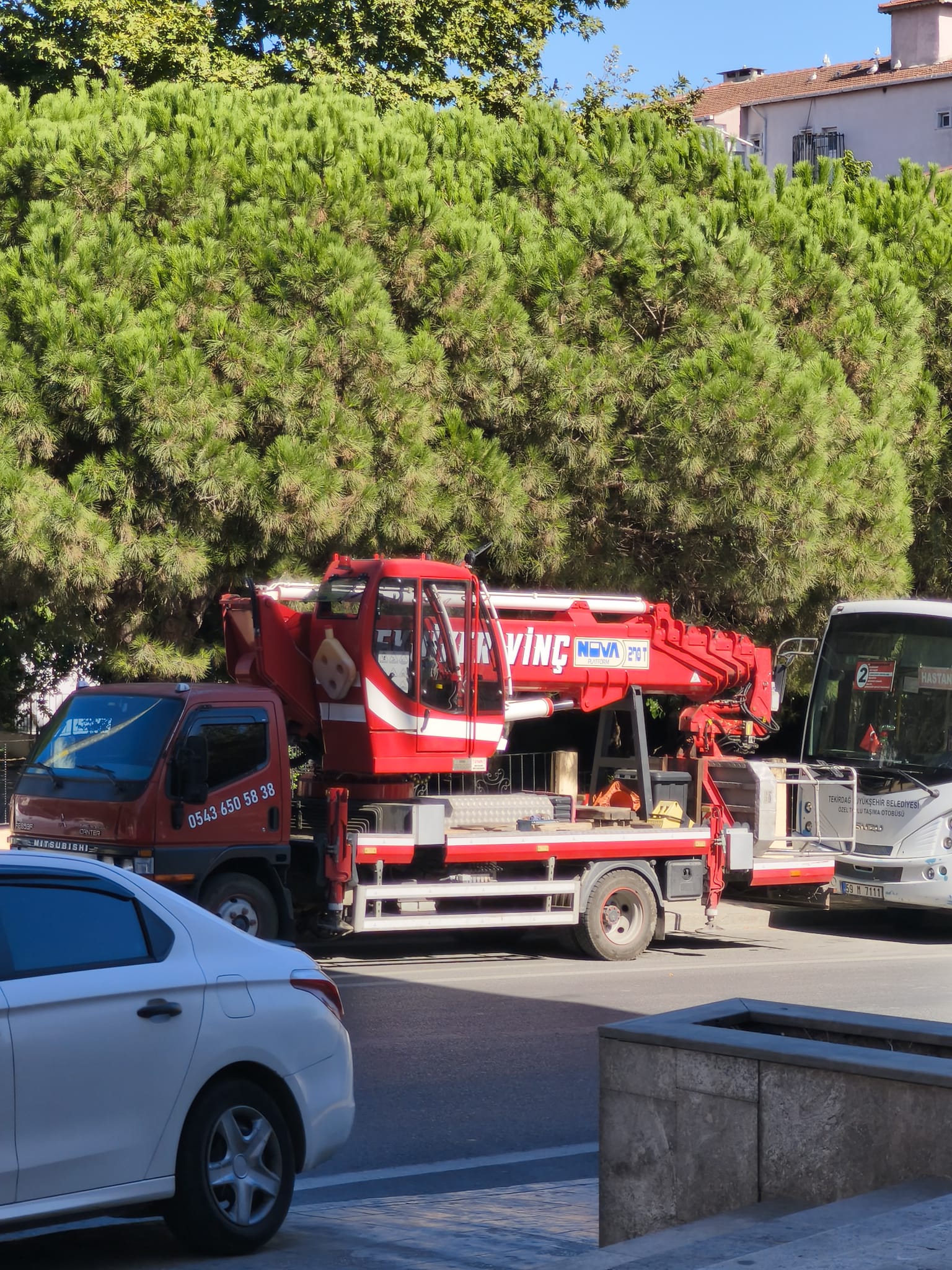 Ağaçlık caddede katlanmış kırmızı kamyon üstü vinç