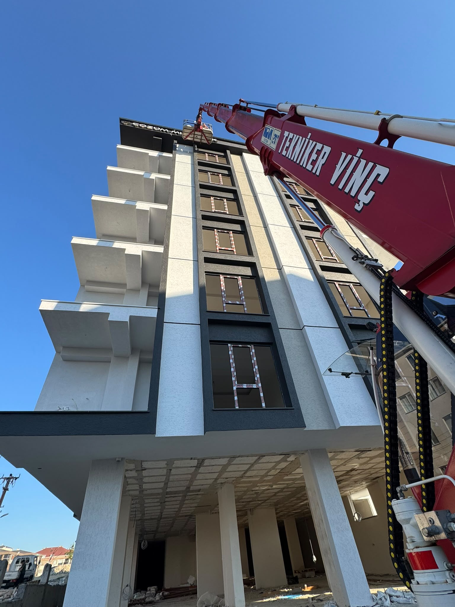 Apartman çatısına uzanan vinç kolunun alttan görünümü