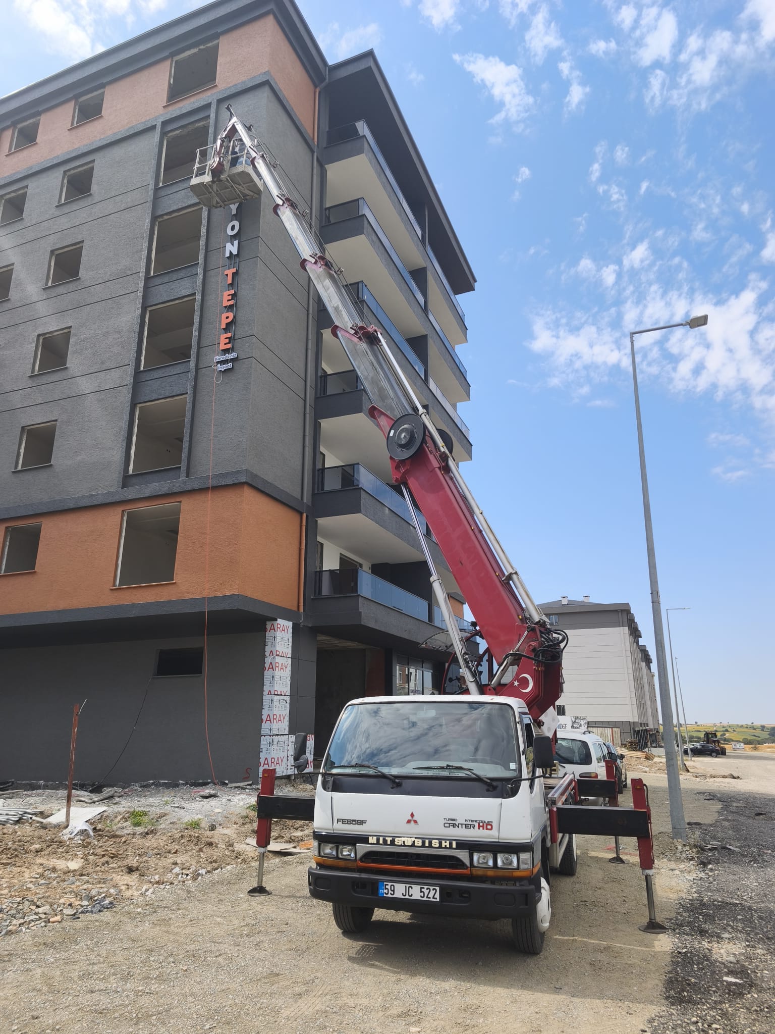 Balkonlu apartmanın üst katında sepetli vinç