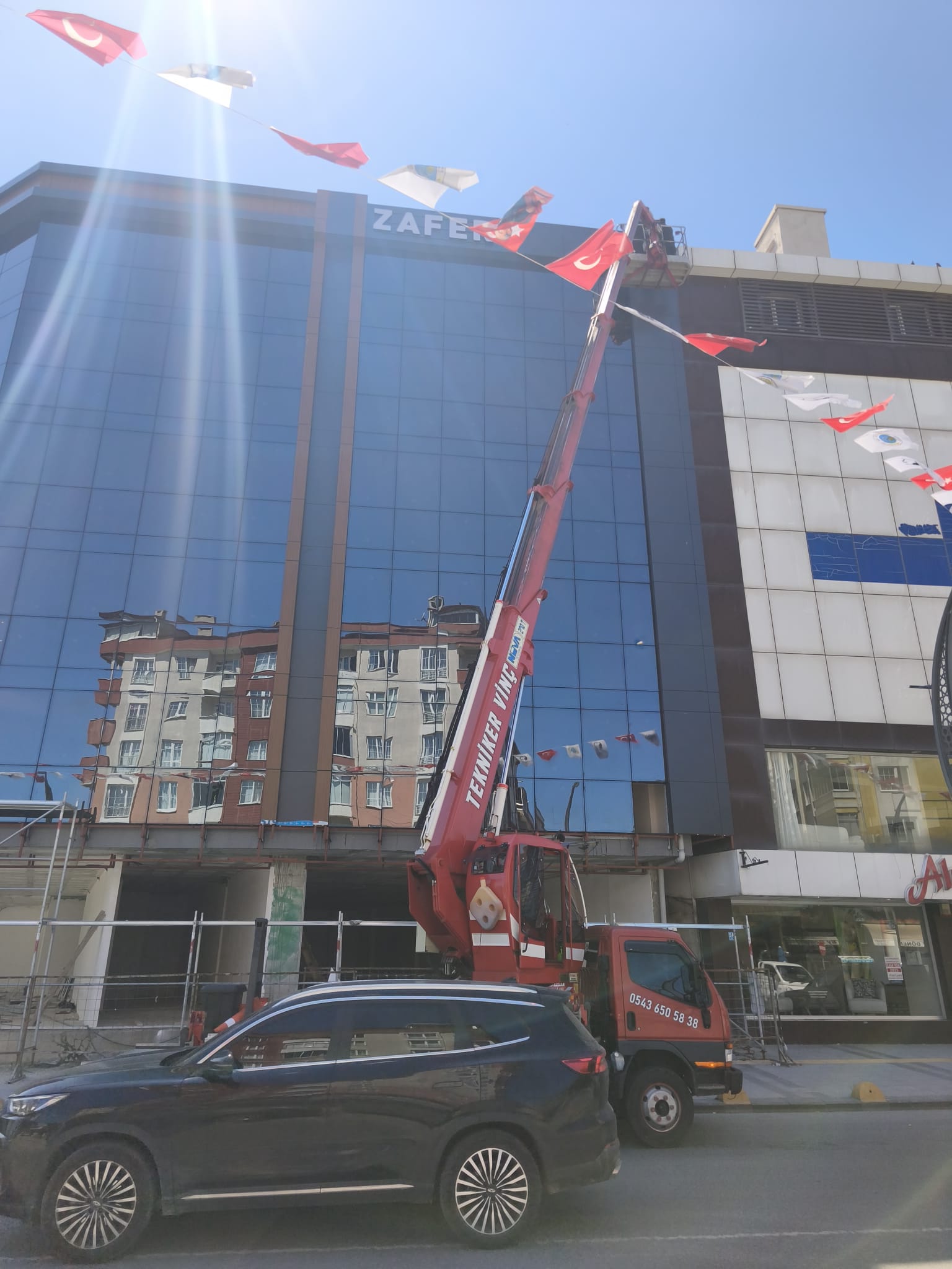 Bayraklı iş merkezinin çatısına uzanan sepetli vinç
