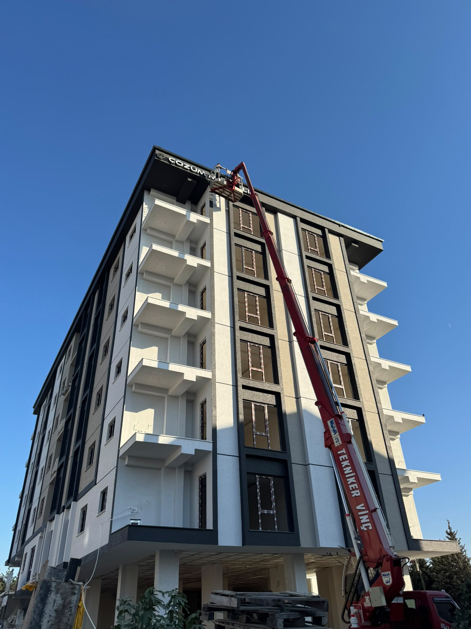 Beyaz balkonlu apartmanın çatısına sepetli vinç ile erişim