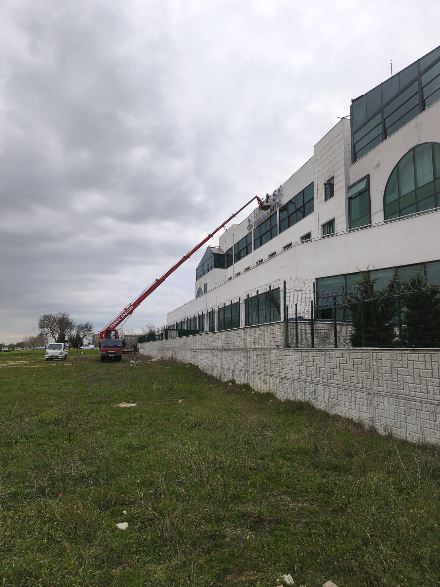 Beyaz fabrika binasında sepetli vinç çalışması