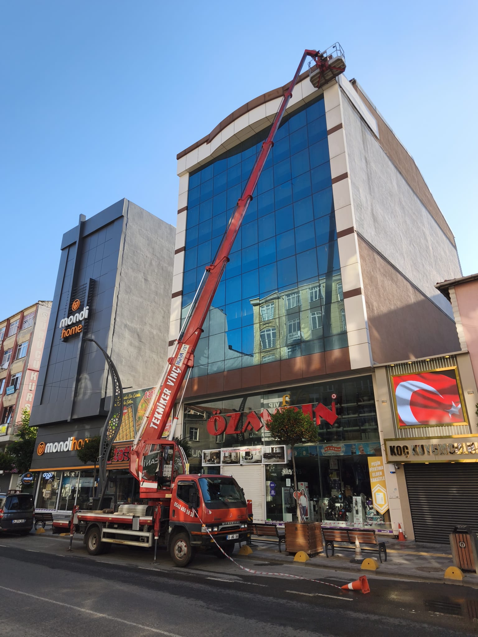 Cam cepheli iş merkezinin çatısında sepetli vinç