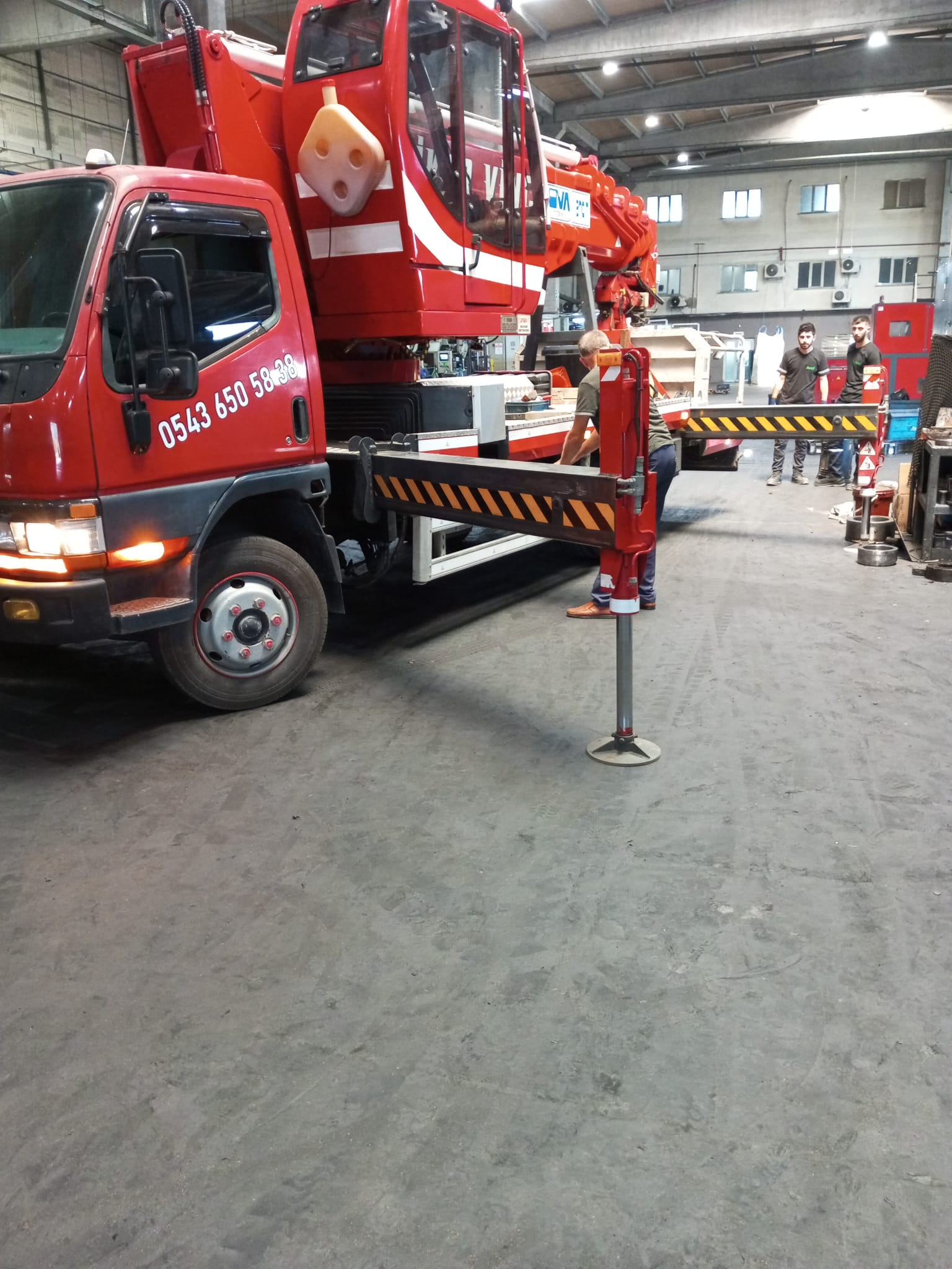 Fabrika içinde destek ayakları açık kamyon üstü vinç