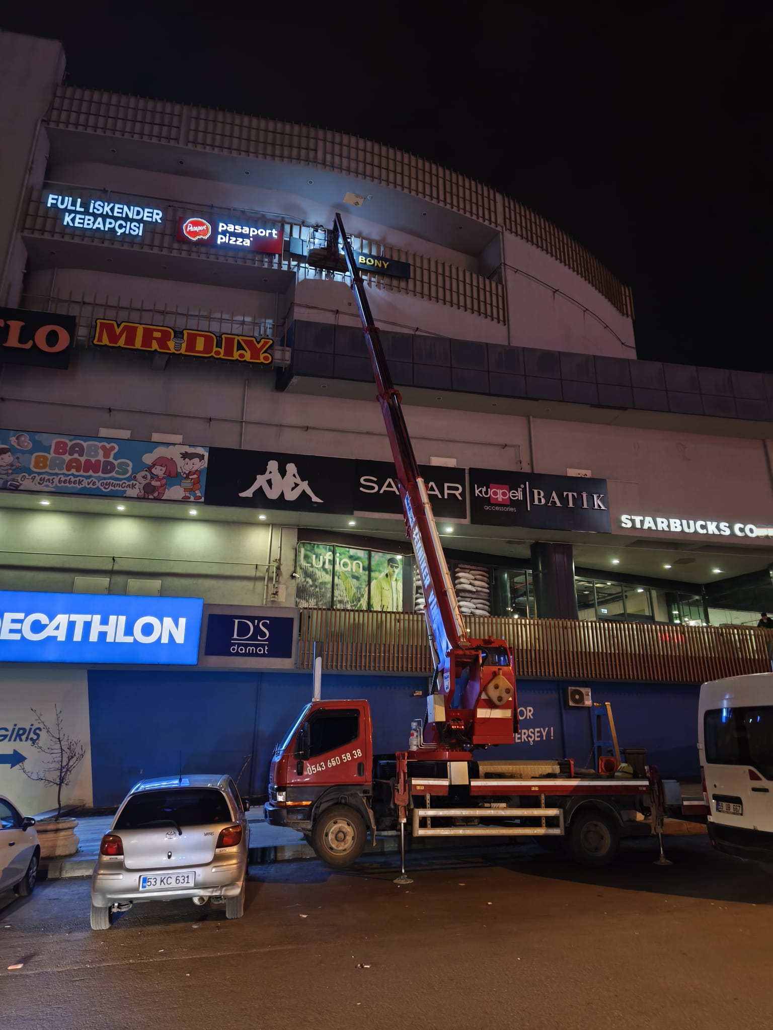 Gece alışveriş merkezi cephesinde sepetli vinç