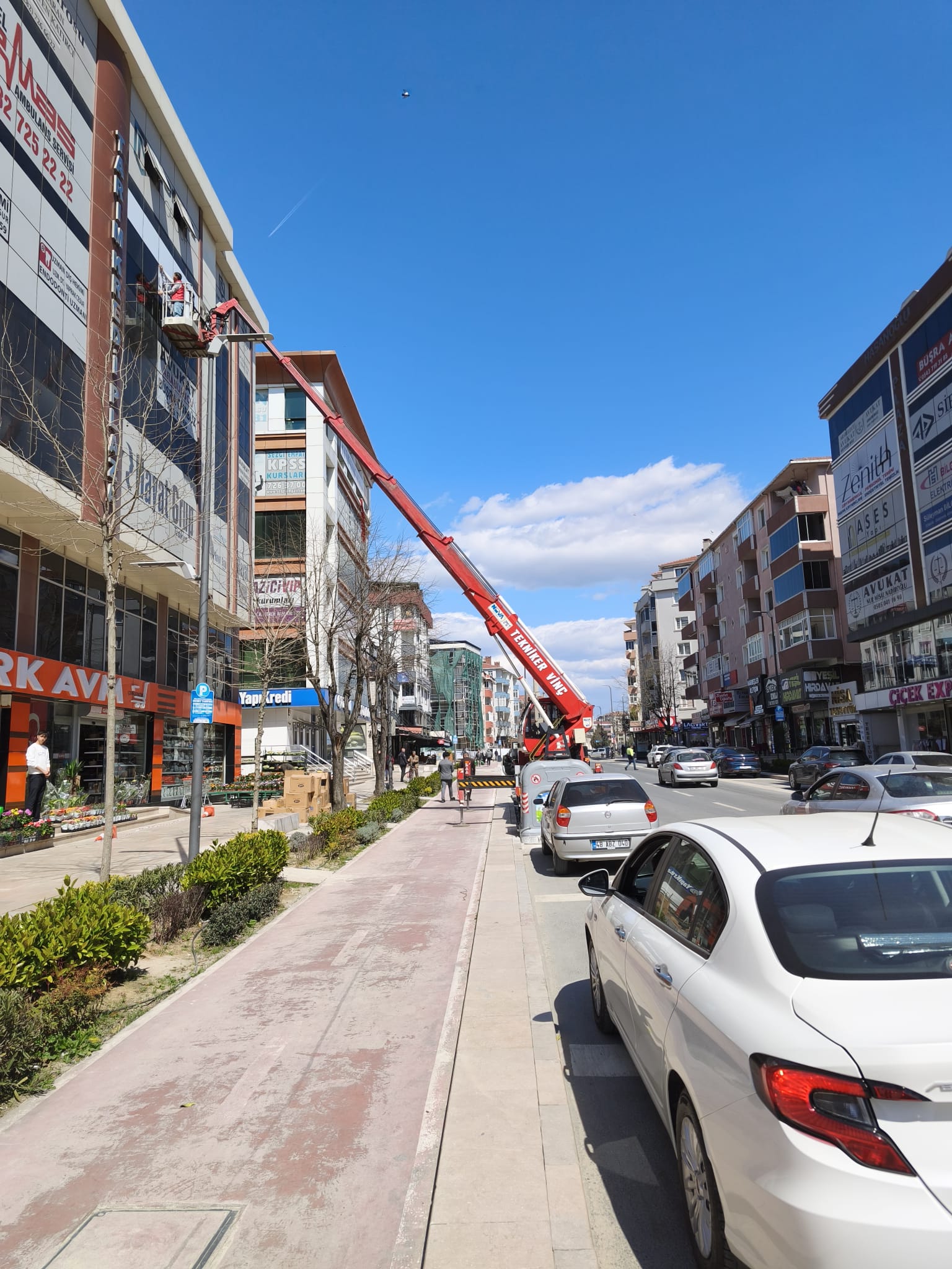 İşlek caddedeki bina cephesinde sepetli vinç