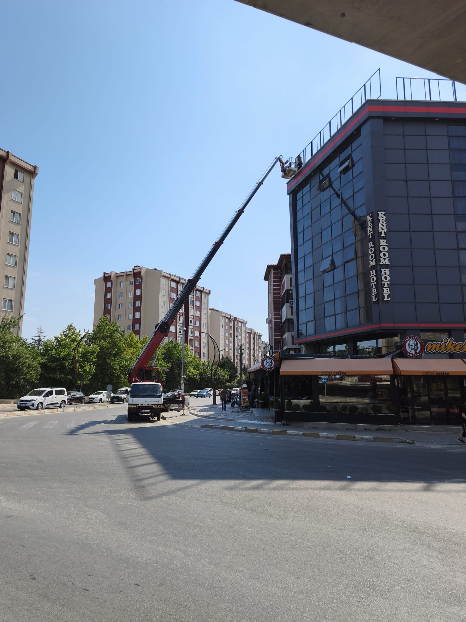 Kavşaktaki cam cepheli binada sepetli vinç