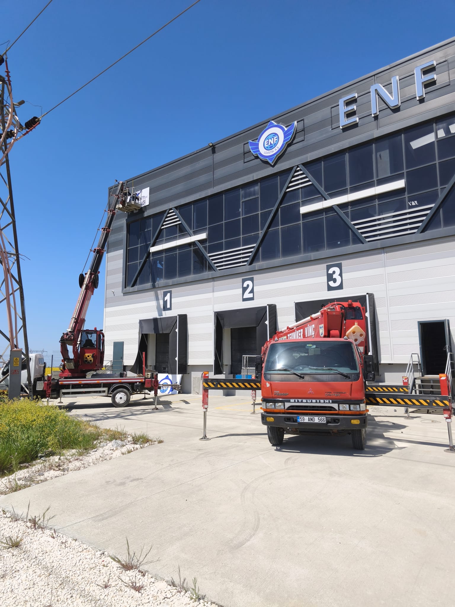 Sanayi deposu önünde iki kamyon üstü vinç