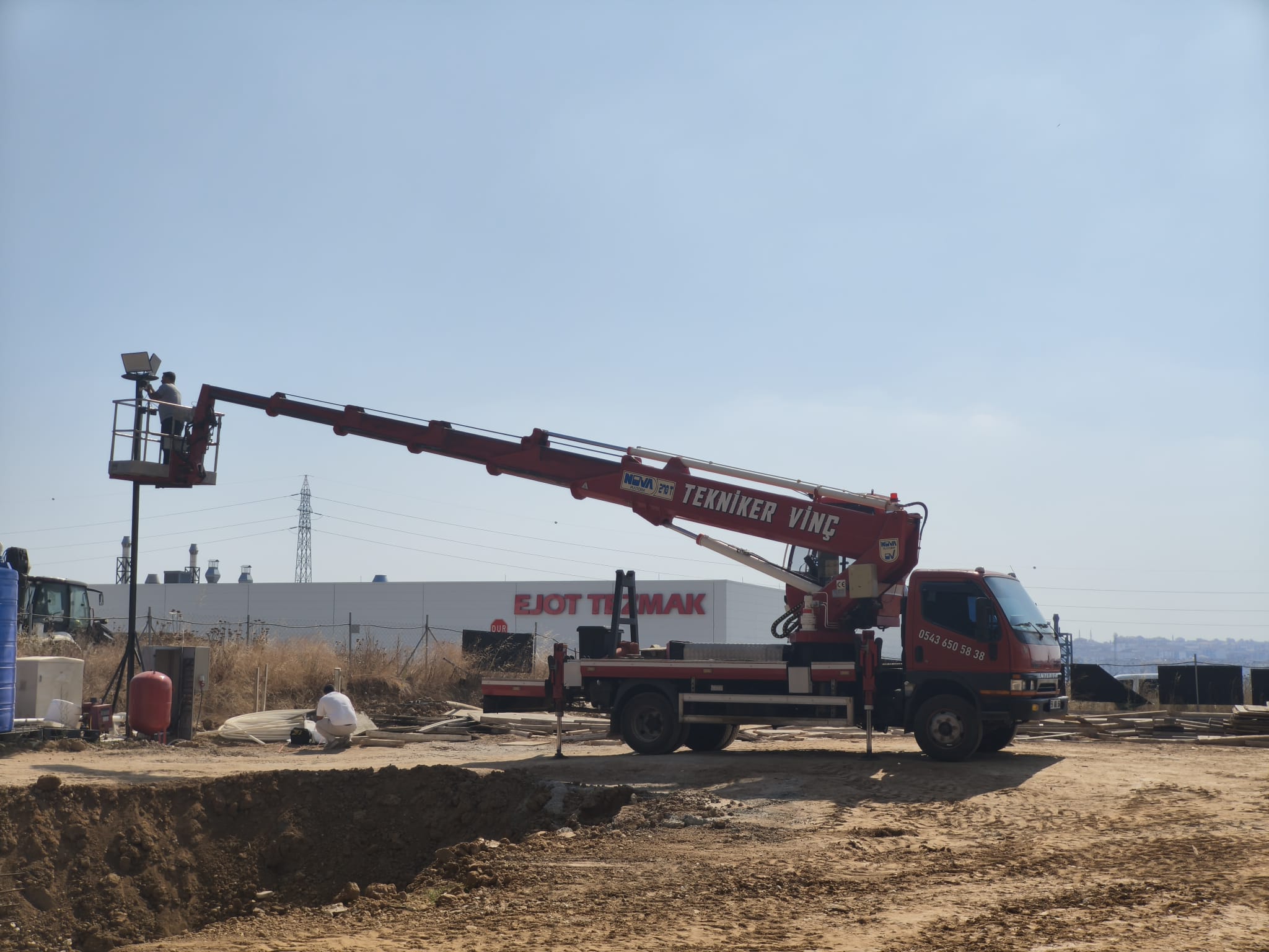 Şantiyede projektör direğine sepetli vinç ile erişim
