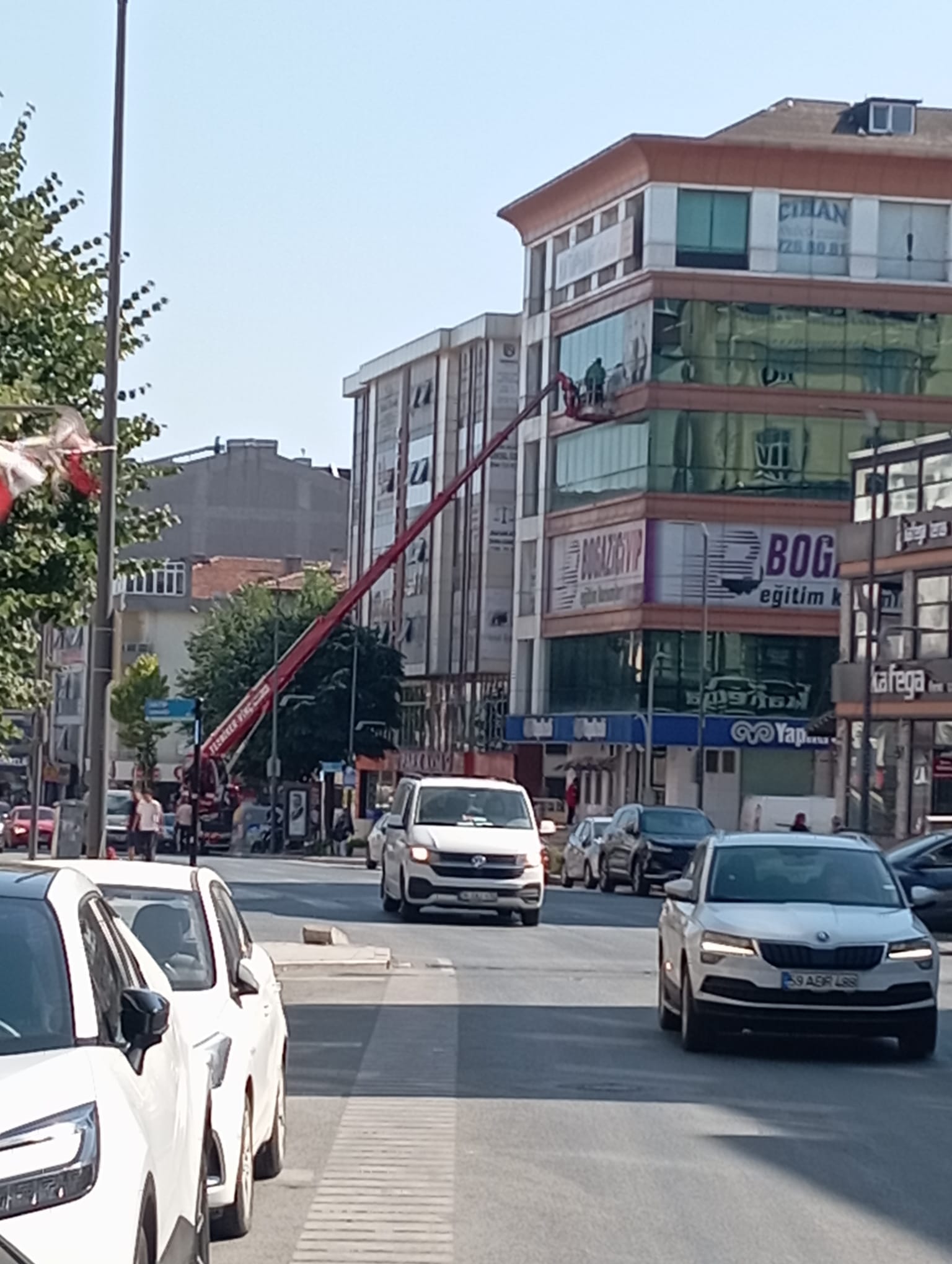 Şehir içi trafikte iş merkezi cephesinde sepetli vinç
