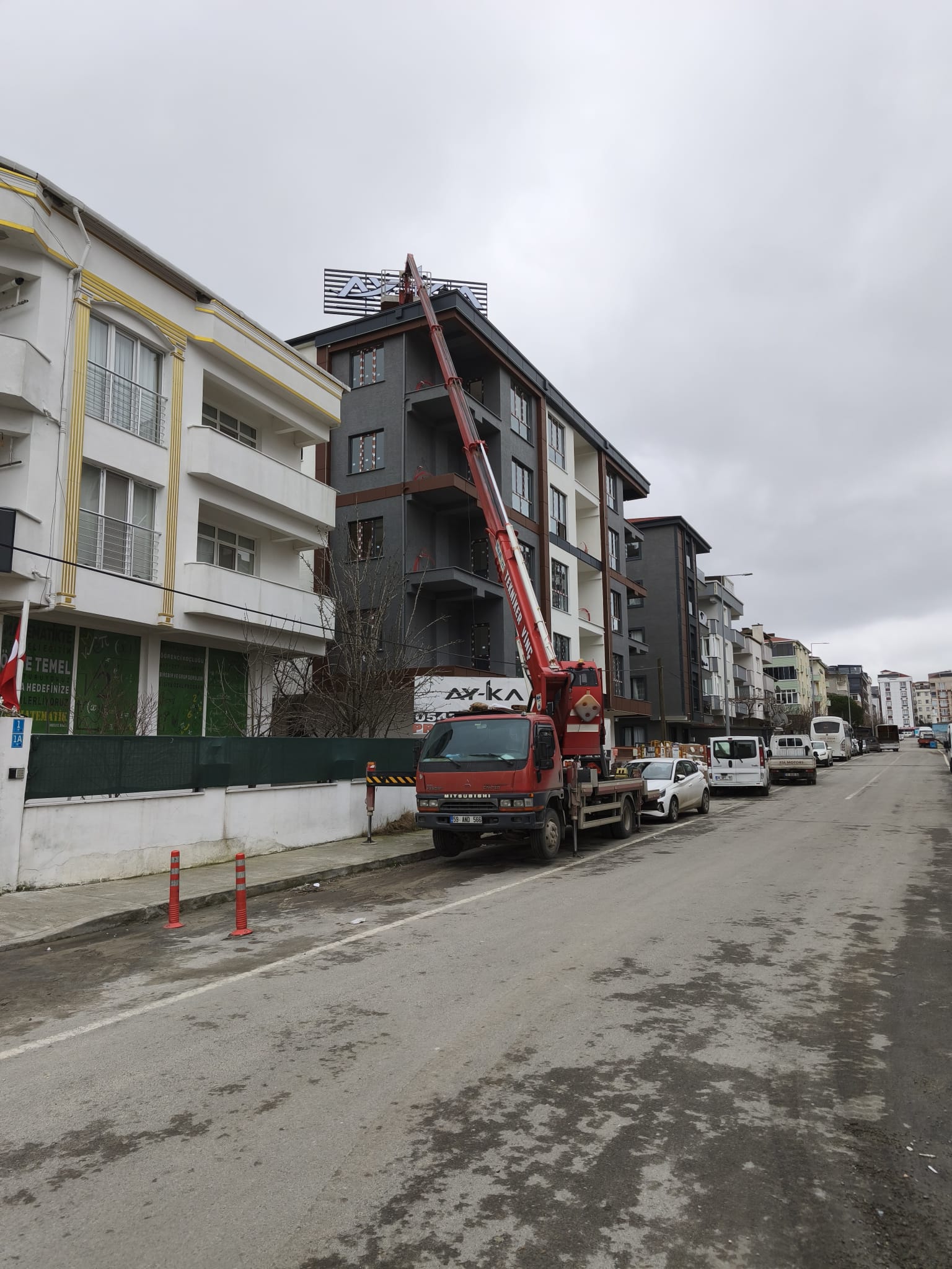 Sokak arasındaki apartmanın çatısında sepetli vinç