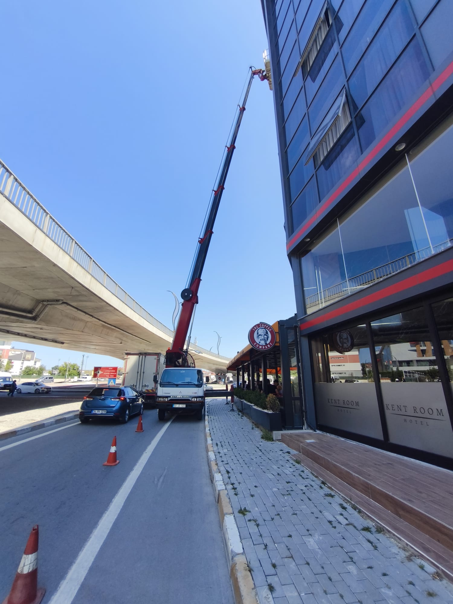 Üst geçit yanındaki cam binada sepetli vinç