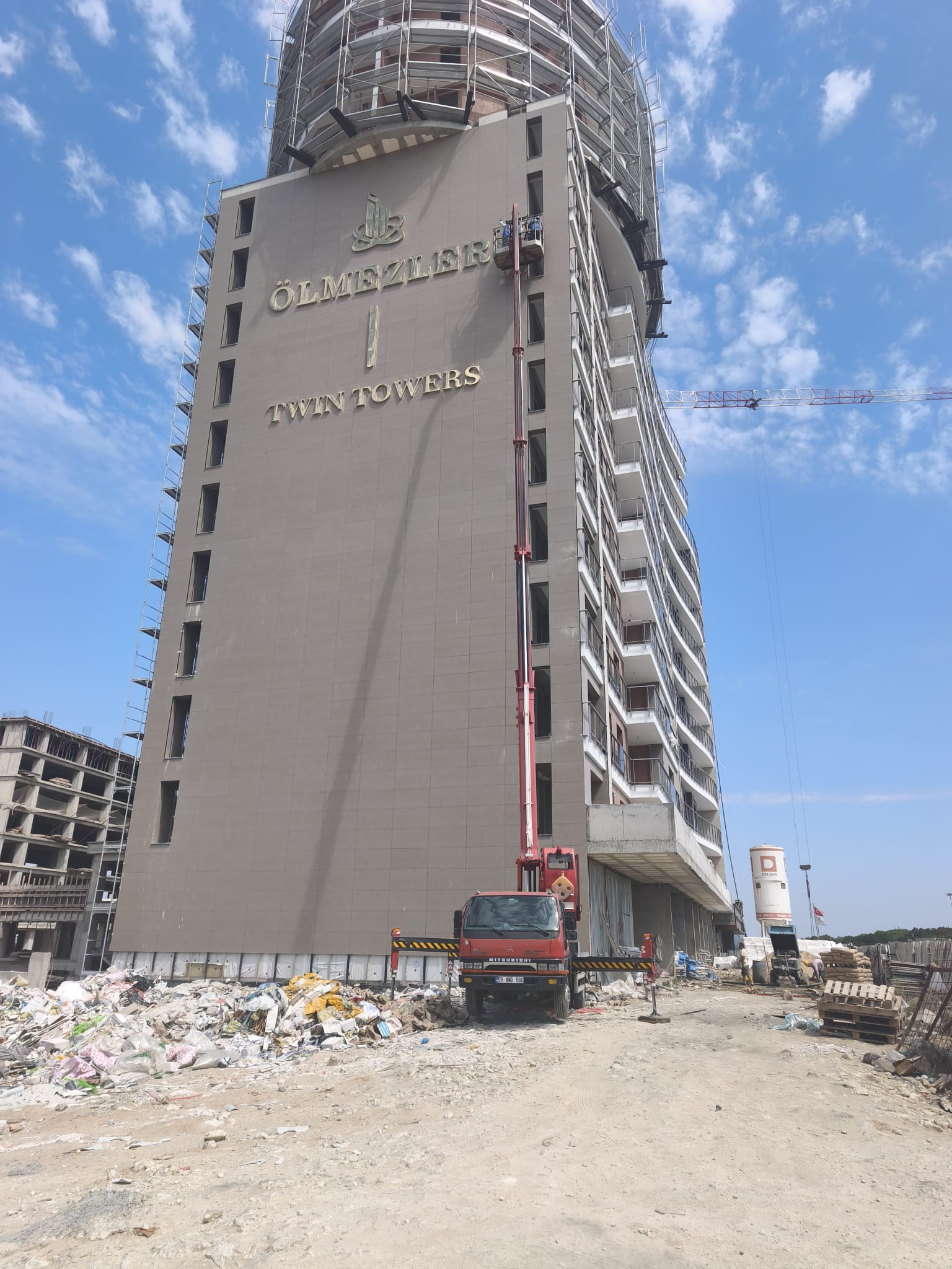 Yüksek bina şantiyesinde dikey uzanan sepetli vinç