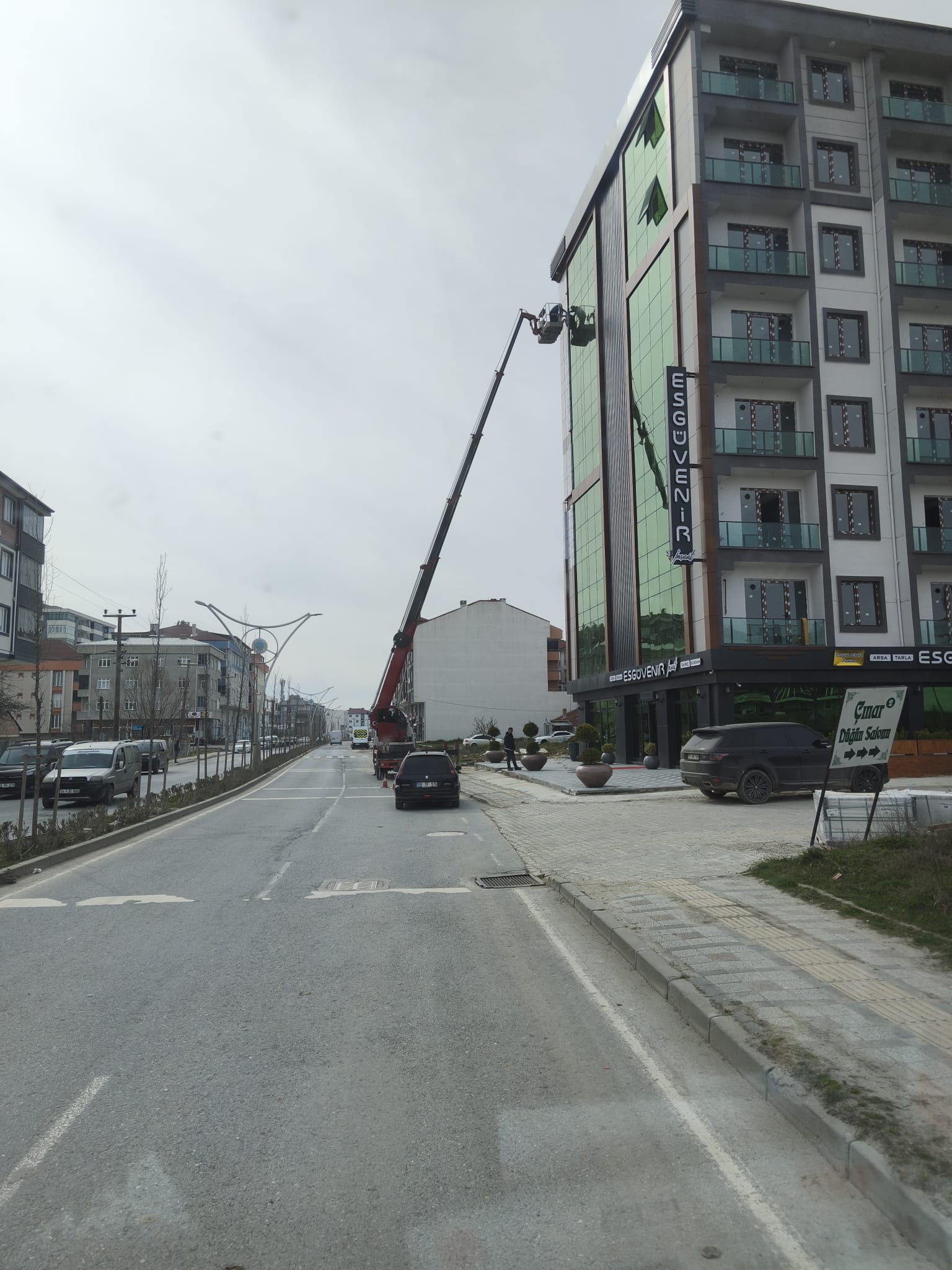 Yüksek binaya uzanan yol kenarındaki sepetli vinç